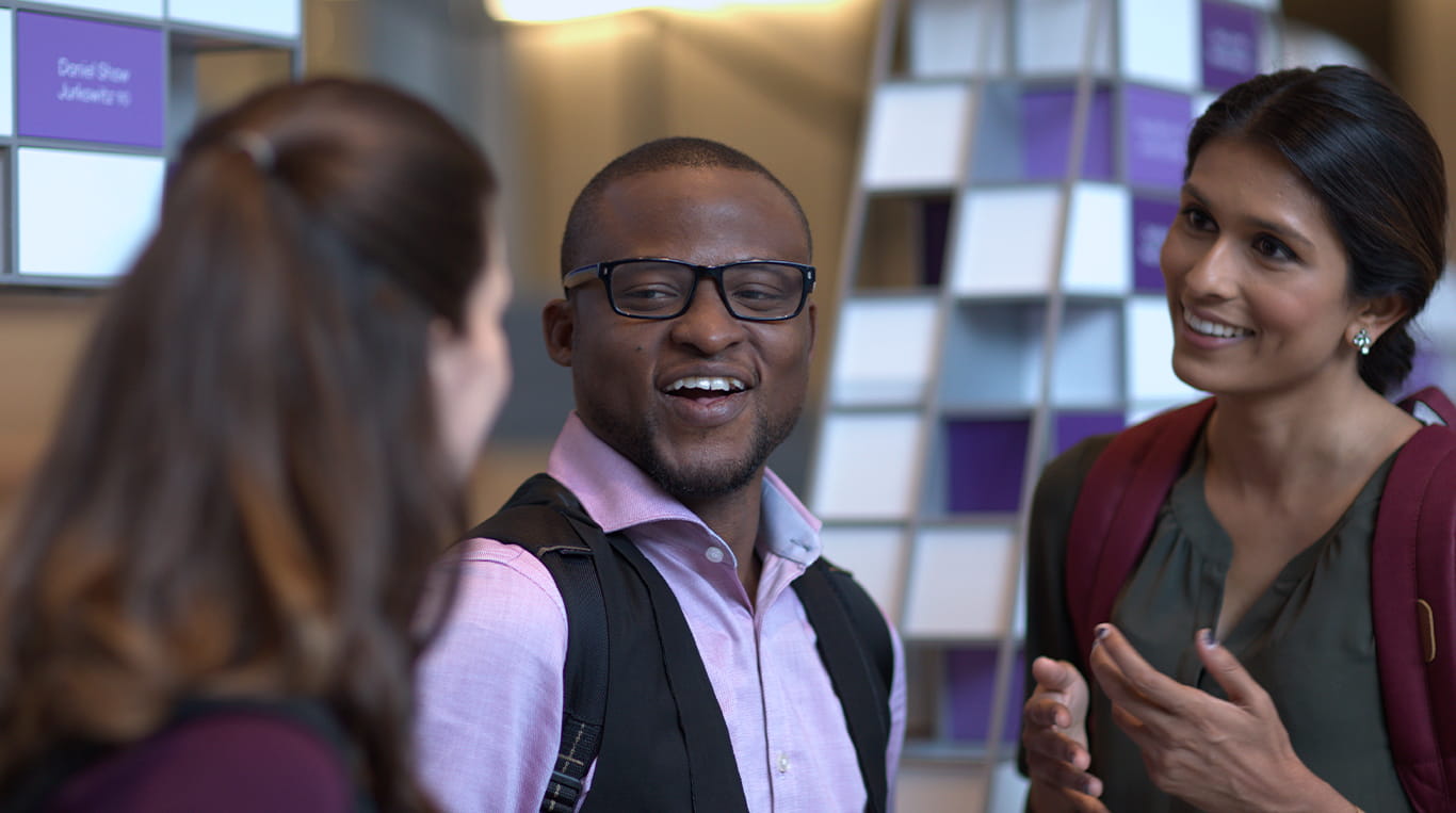 Three Kellogg students stand in a group and have a casual chat in the Kellogg Global Hub in Evanston, Illinois.