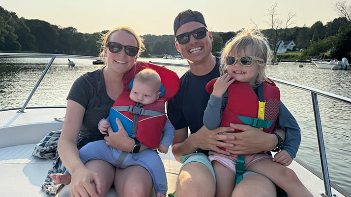 Michael Konaires '22 MBA and his family sit on a boat on a lake on a sunny day.
