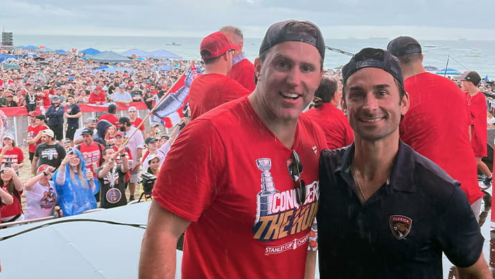 Kellogg graduates Matt Caldwell and Matt Zarthar smile together looking out at the crowd at the Florida Panthers Stanley Cup Championship parade.