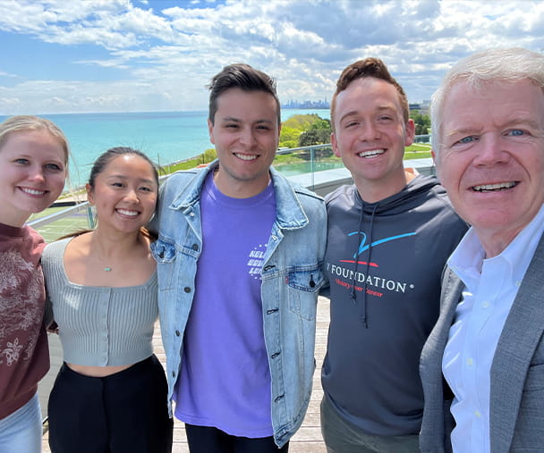 A group of five people posing for a selfie in front of Lake Michigan.