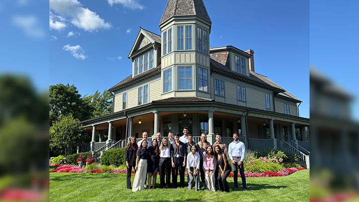 A group of students posing outside a house.