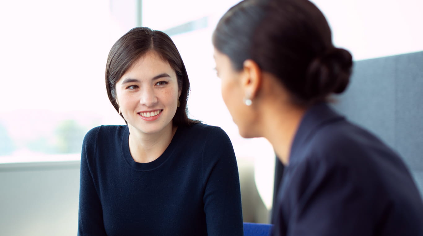 Two professional women discussing career journeys