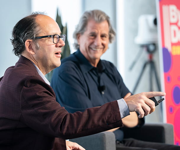 Two men on stage engaging talking with one another about the role design plays in business