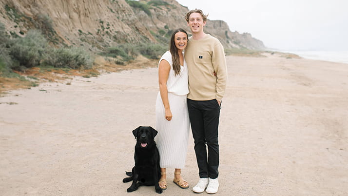 A man and a woman on the beach with their dog.