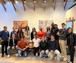 A group of Kellogg students smile and pose together near colorful artwork, while on a Levy Trek in San Francisco to learn about AI and entrepreneurship.