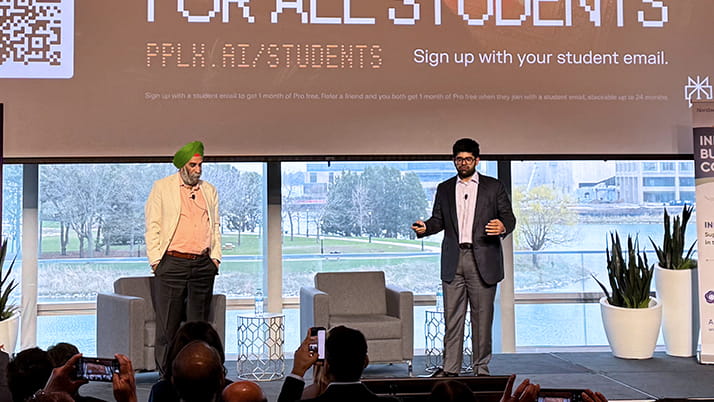 Two men speaking in front of a crowd during a conference