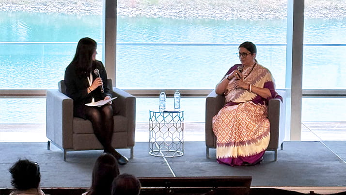 Two women on stage talking with each other during a conference panel session.