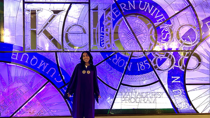 A Kellogg alumna standing in front of glass stained windows