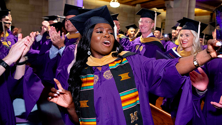 A Kellogg student wearing a purple gown and black cap dances as she celebrates at the EMBA convocation 2025.