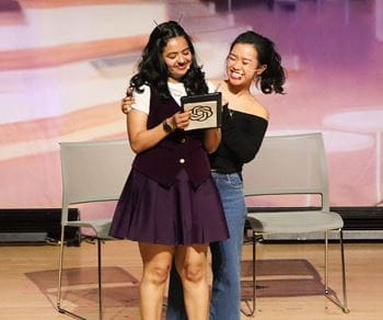 Two female MBA students on stage performing at a school event