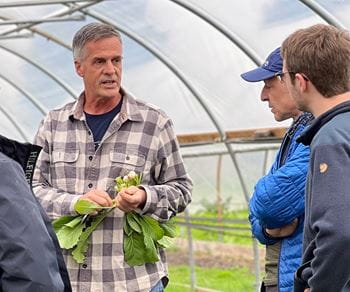 A man in a greenhouse with a group of Kellogg MBA students