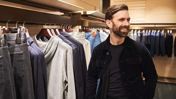 Ian Rosen smiles while looking through a rack of clothing at high-end menswear boutique Harry Rosen.