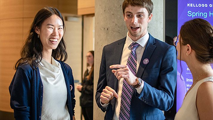 Two female MBA students and male peer talking during a conference break.