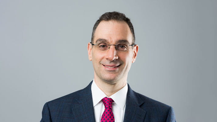 Man with glasses wearing a red tie and business suit