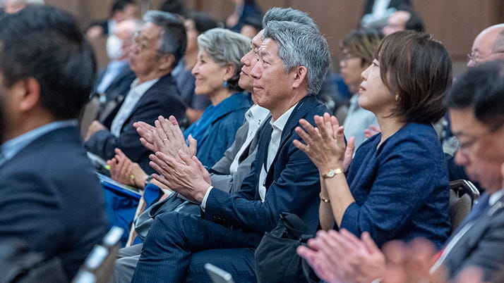 Men and woman clapping from their seats during a speaking session.