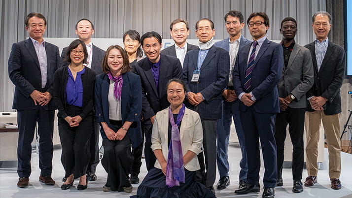 A mix of men and woman with hands folded in front of them posing for a group picture