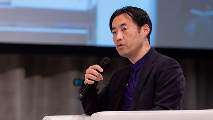 An Asian man with a focused look as he holds a mic in his hand.