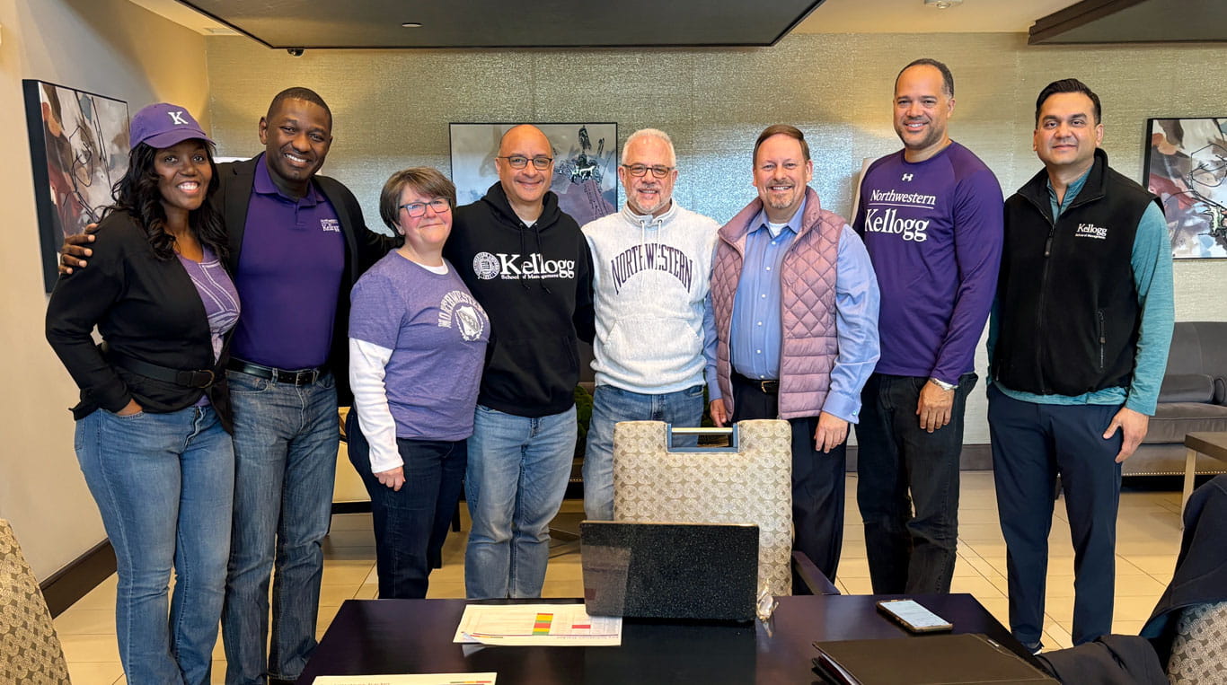 Graduates from Kellogg School of Management standing next to one another and wearing purple.