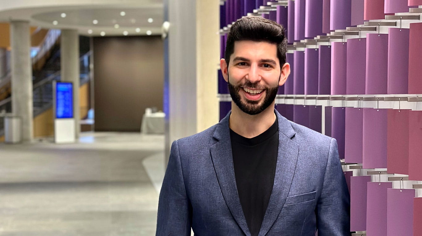 A man with a beard wearing a sport coat and standing next to a colorful wall