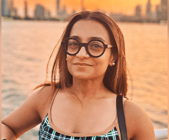A woman wearing glasses near a lake