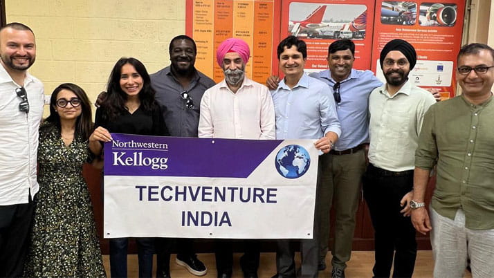 A group of MBA students and a faculty member holding a banner for their immersion trip
