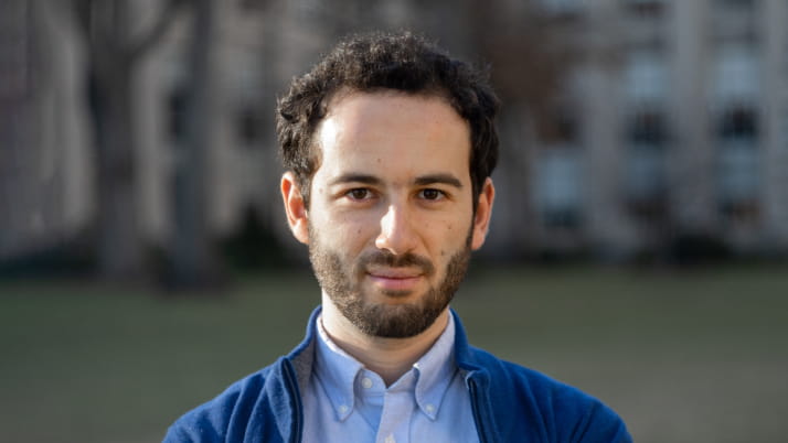 Man with beard wearing a collared blue shirt and sweater