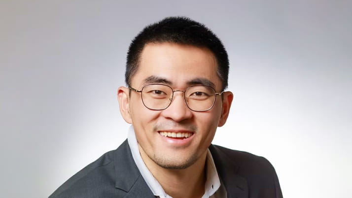 A smiling Asian man wearing glasses
