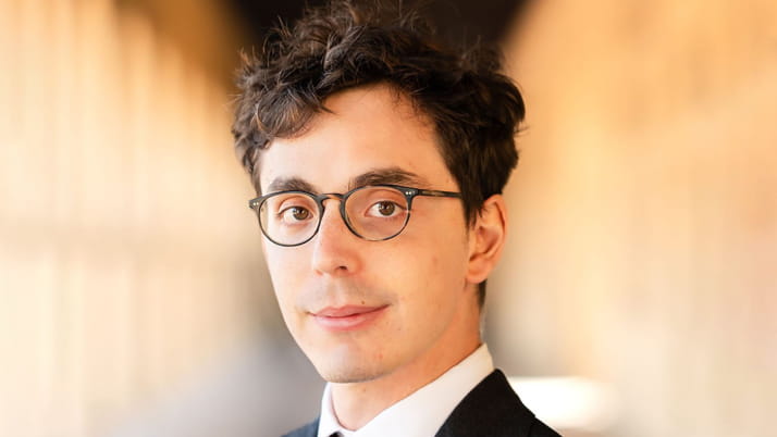 A man with brown hair smiling faintly