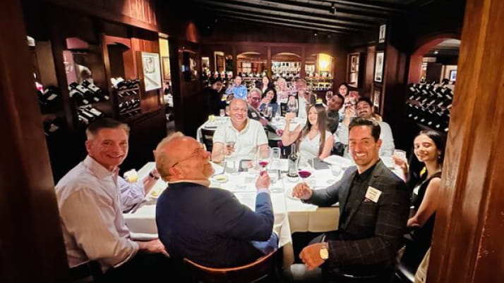 A group of men and a woman sitting at a dinner table.