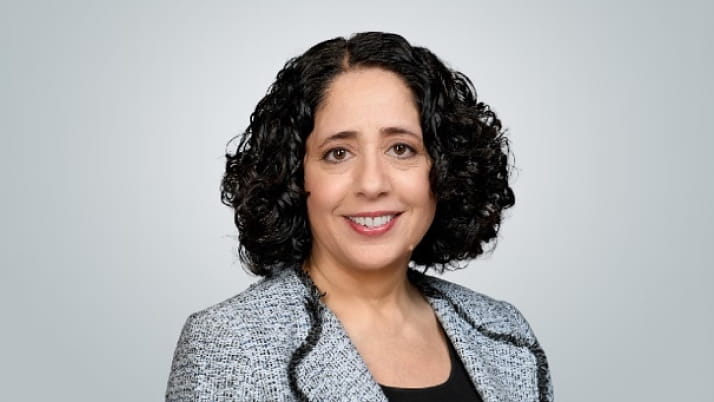 Woman with curly dark hair wearing a patterned blazer