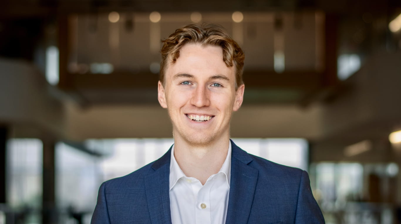 A white man wearing a button down shirt with a blue blazer
