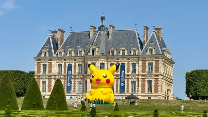A giant inflatable Pokemon figure in front of a chateau