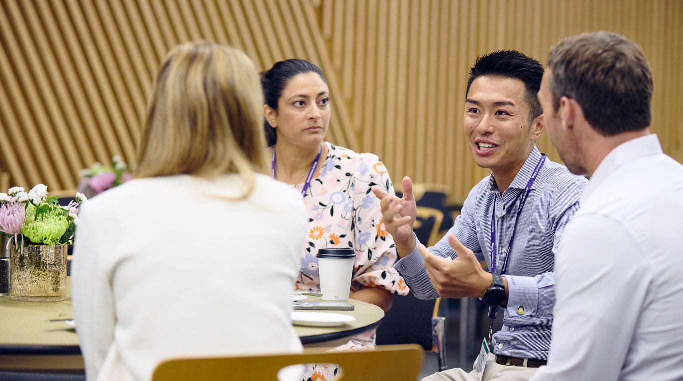 A group of people talking with one another around a table