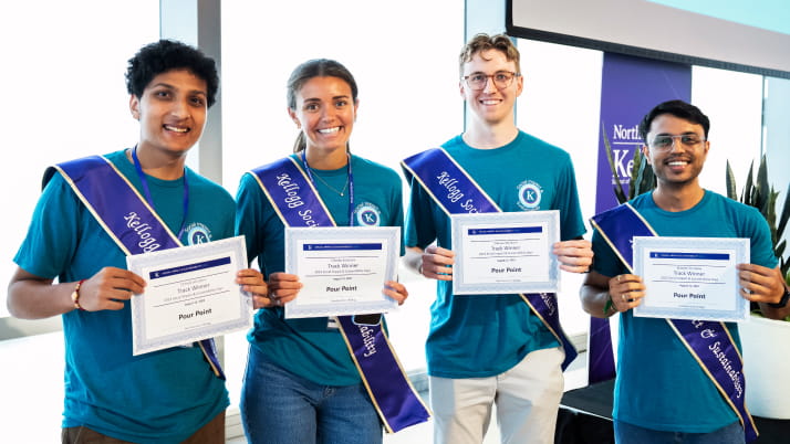 A group of three men and one woman wearing sashes and smiling, as each holds a winning certificate.