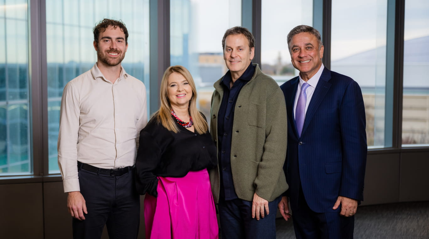 Three men and a woman standing in front of a window smiling