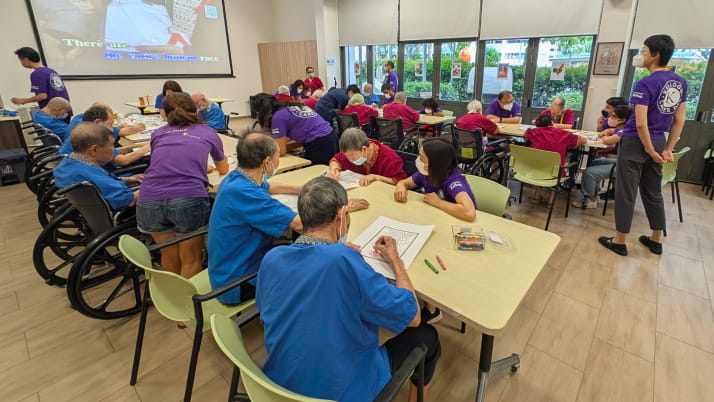 A group of older Asian adults sitting in room and playing bingo
