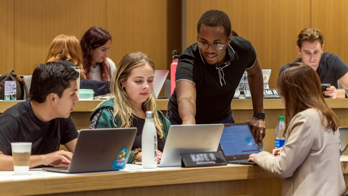 A group of people working together around laptops in a classroom