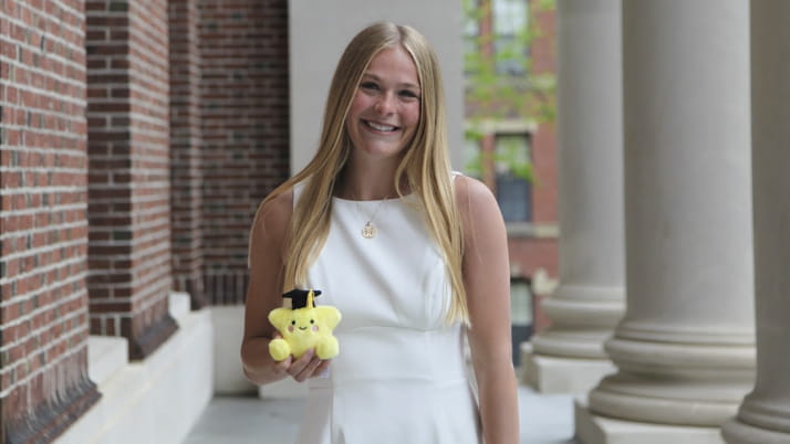 A young woman wearing a white dress and holding a stuffed animal in one hand