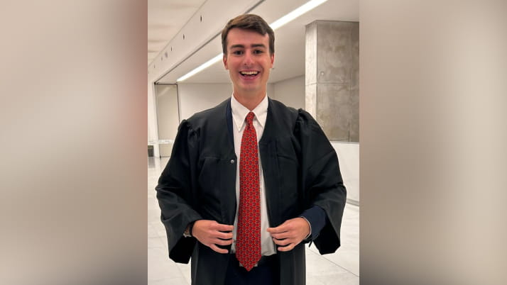 A young man smiling and wearing a white dress shirt with a red tie