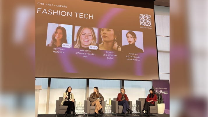 Four people sitting in chairs on an elevated stage with a projector screen behind them that reads: Fashion Tech