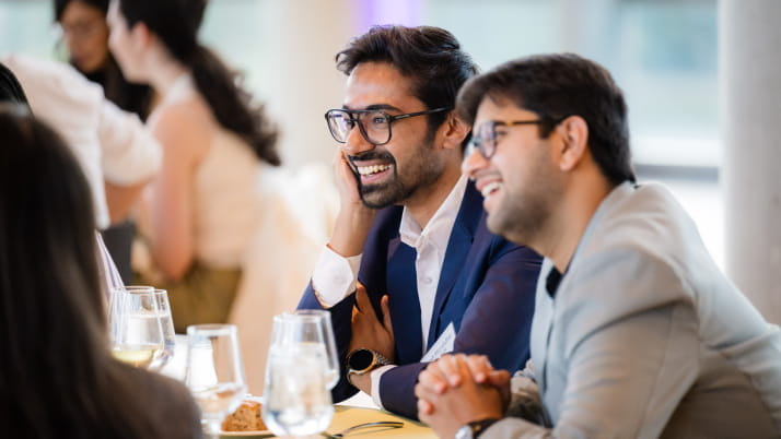 Two men in business attire sitting down and smiling