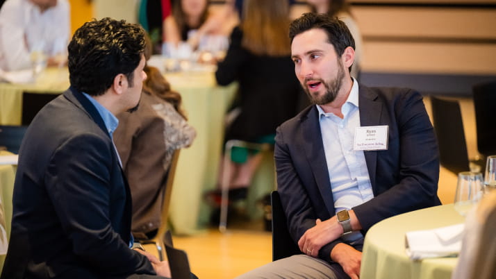 two men sitting at a table talking with each other