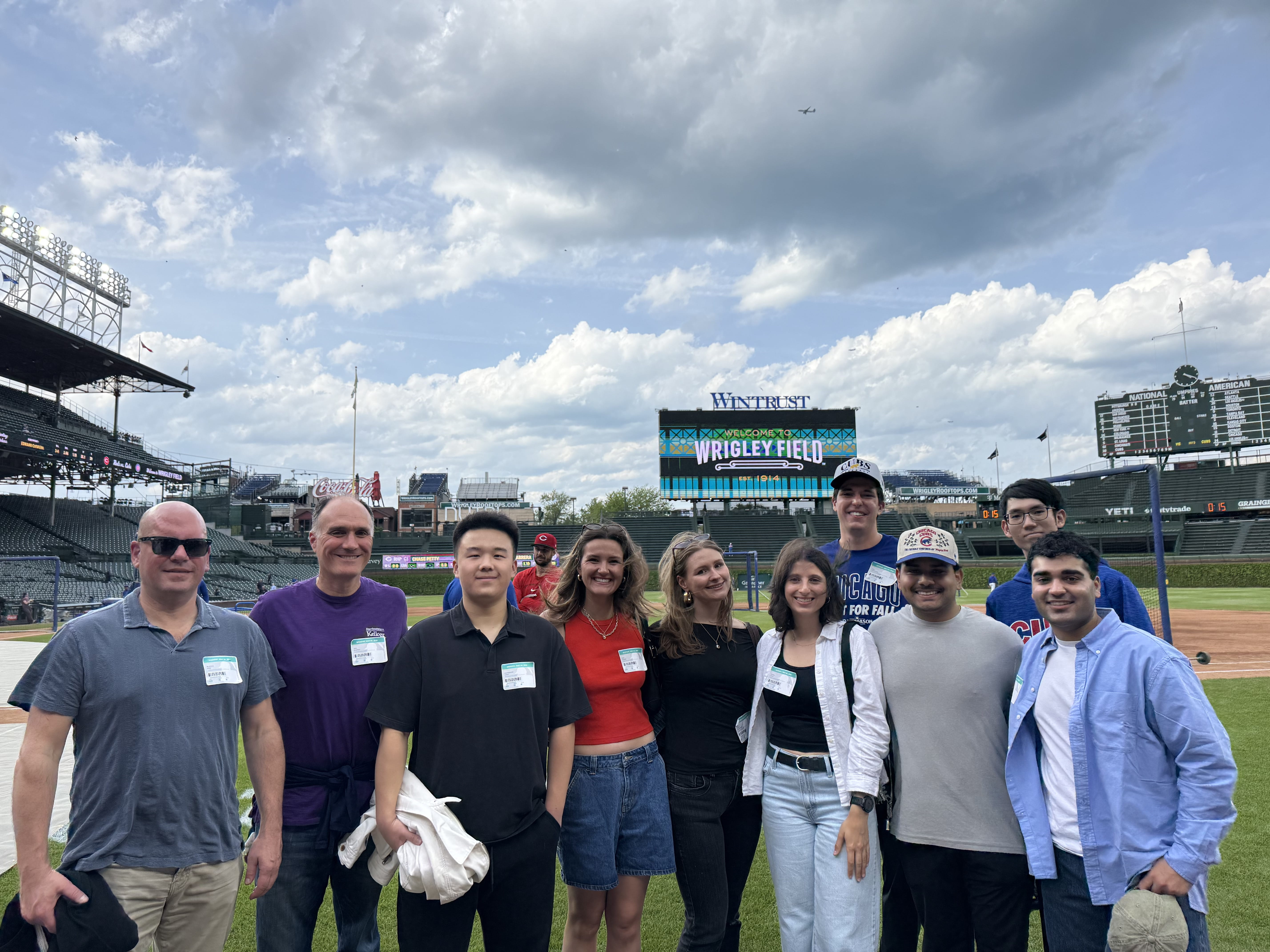 Kellogg students and professors stand on a baseball field