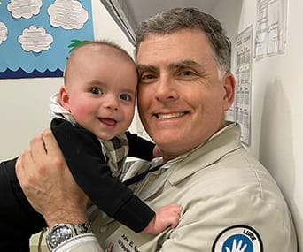 John Fortunato, MD, holds a baby in a doctor's office.