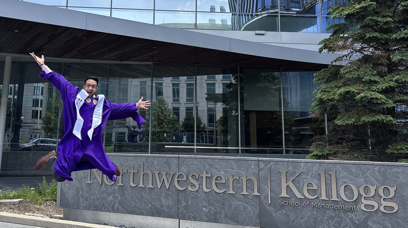 Ryan Ghosh jumps in front of the Kellogg sign outside of the Global Hub.