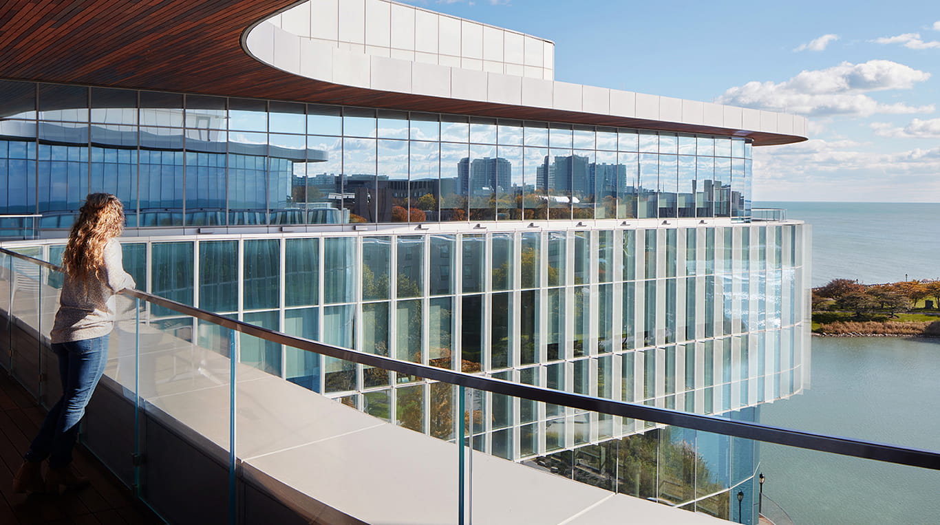 A woman looks out at the horizon from a balcony at the Kellogg Global Hub building.