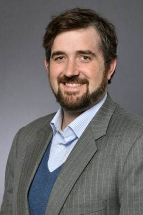 A person wearing a suit and tie smiling at the camera

Description automatically generated