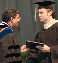 Dean Jain shaking the hand of a new Kellogg grad